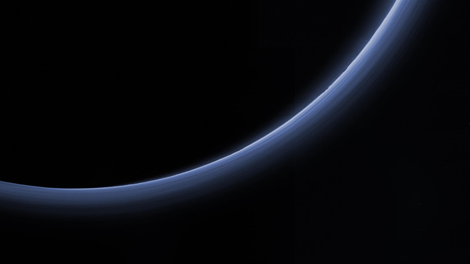 Pluto im Gegenlicht mit erkennbaren Dunstschichten in annähernd Echtfarbe
